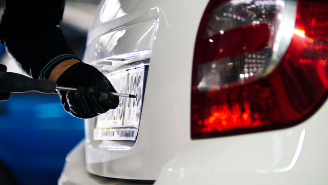 man fixing a numberplate onto a car in a car dealership